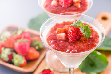 Delicous and nutritious double color (colour) strawberry desserts with mint and diced sarcocarp topping isolated with airy blue background, copy space, close up