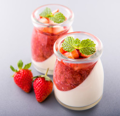 Delicous and nutritious double color (colour) strawberry desserts with mint and diced sarcocarp topping isolated with airy blue background, copy space, close up