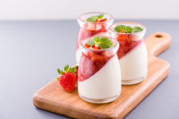 Delicous and nutritious double color (colour) strawberry desserts with mint and diced sarcocarp topping isolated with airy blue background, copy space, close up