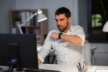 business, technology and time management concept - businessman using voice command recorder on smart watch at nigh office