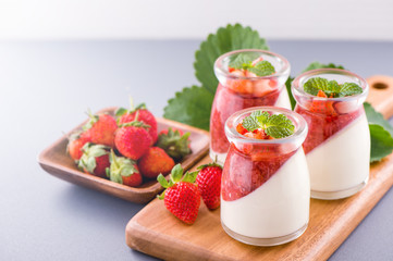 Delicous and nutritious double color (colour) strawberry desserts with mint and diced sarcocarp topping isolated with airy blue background, copy space, close up