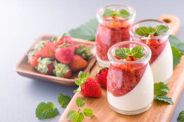 Delicous and nutritious double color (colour) strawberry desserts with mint and diced sarcocarp topping isolated with airy blue background, copy space, close up
