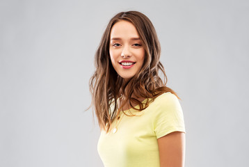 people concept - smiling young woman or teenage girl in blank yellow t-shirt over grey background