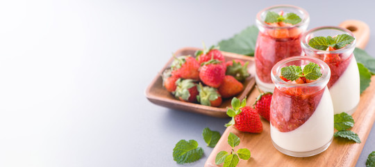 Delicous and nutritious double color (colour) strawberry desserts with mint and diced sarcocarp topping isolated with airy blue background, copy space, close up