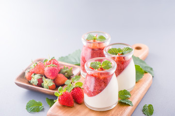 Delicous and nutritious double color (colour) strawberry desserts with mint and diced sarcocarp topping isolated with airy blue background, copy space, close up