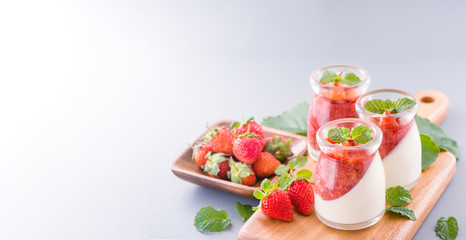 Delicous and nutritious double color (colour) strawberry desserts with mint and diced sarcocarp topping isolated with airy blue background, copy space, close up