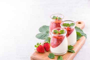 Delicous and nutritious double color (colour) strawberry desserts with mint and diced sarcocarp topping isolated with airy blue background, copy space, close up