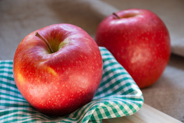 Two red apples on green and white checkered cloth. Close-up focused