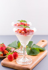 Delicous and nutritious double color (colour) strawberry desserts with mint and diced sarcocarp topping isolated with airy blue background, copy space, close up