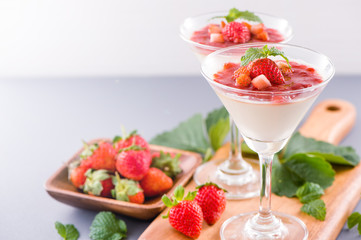Delicous and nutritious double color (colour) strawberry desserts with mint and diced sarcocarp topping isolated with airy blue background, copy space, close up