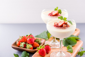 Delicous and nutritious double color (colour) strawberry desserts with mint and diced sarcocarp topping isolated with airy blue background, copy space, close up