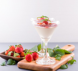 Delicous and nutritious double color (colour) strawberry desserts with mint and diced sarcocarp topping isolated with airy blue background, copy space, close up