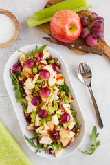 Waldorf salad with apples, celery, grapes, walnuts and arugula on white plate, top view - 250032454