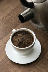 preparing hot coffee into a white mug