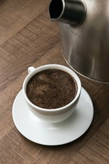preparing hot coffee into a white mug