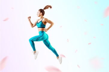 Young woman runner in blue sportswear jump in the air.