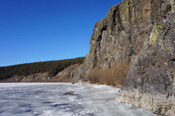 Fototapeta na wymiar Mountain cliffs on the bank of the river against the blue sky