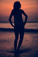 Fototapeta premium Silhouette of a girl in sunset / sunrise time over the ocean.