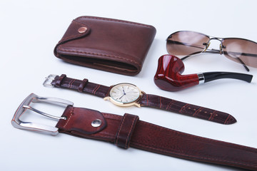 Men's accessories for business and rekreation. Leather belt, wallet, watch and smoking pipe on white background.. Top view composition.