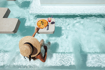 Girl eating pizza in pool