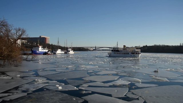 View over harbor and bridge from the Essingen island a sunny spring day over a ice covered lake Malaren,  Commuter boat leaving