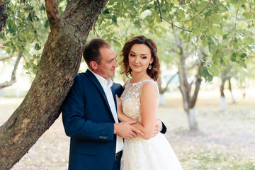 young bride and groom walking in a summer Park with green trees