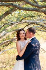 young bride and groom walking in autumn Park with yellow leaves