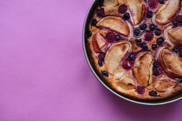 Delicious authentic hand-made homemade pie with apples and berries on a pink background texture. baking recipe to cook