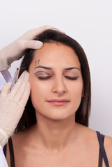 Fototapeta premium Portrait Of Beautiful Smiling Woman With Closed Eyes And Black Surgical Lines On Skin. Closeup Of Hands Touching Young Female Face. Plastic Surgery Concept.