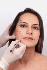 Surgeon drawing surgical lines on beautiful woman's face