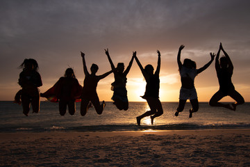 silhouette of women jumping at sunset on the beach - 250038424