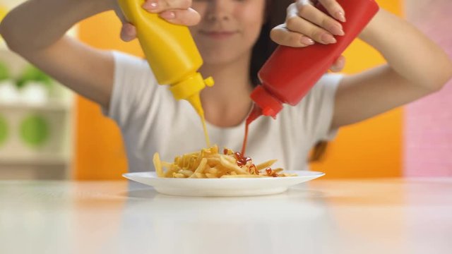 Smiling lady pouring ketchup and mustard on french fries plate, unhealthy meal