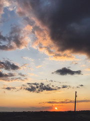 Construction site crane or oil pump silhouette in beautiful amazing sunset. Blue and yellow sky with clouds, atmospheric scene of new construction in evening or morning. Environment pollution