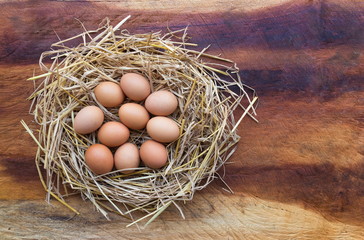 Top view of Chicken, Easter eggs in nest on a wooden table background, image with copy space.