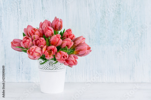 Pink tulips bouquet in white vase on blue background. Holiday background, copy space. Valentine Day, Mothers day, birthday concept.