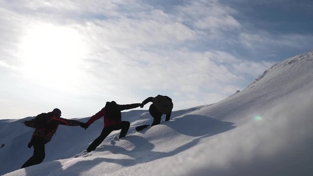 Tourists climbing a mountain snow cliff. Stretching a helping hand. People help each other. Teamwork, teamwork concept