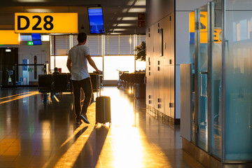 Man walking towards airport gate with roller suitcase