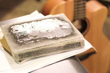 thick old book with battered crusts in the foreground, blurred guitar background