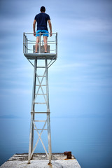 Lifeguard stands on a tower on the beach and looks into the sea