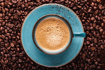 freshly brewed coffee crema in a cup on coffee beans bedded
