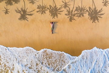 The guy lies on a sandy beach on a tropical island. Drone view