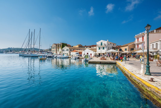 Old port Galios on Paxos island with anchored yachts, boat in background, street lamp in front