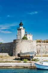 The old lighthouse on fortress wall. Below are two wooden ships.