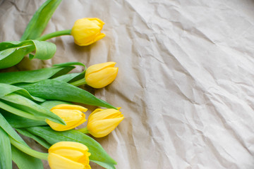 Obraz premium Bouquet of yellow tulips on wrapping paper. Valentine's Day and Mother's Day background. Top view Copy Space.