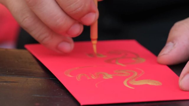 Vietnamese scholar write calligraphy at lunar new year. Calligraphy festival is a popular tradition during Vietnam Tet holiday. Calligrapher draw handwriting in penmanship at fair in springtime