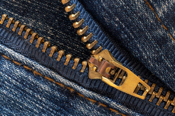 Denim or rough cotton fabric or jeans material with the zipper for the textile textured background of pale blue color. Macro shot