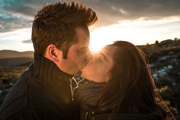 Young romantic couple kissing at a sunset in the countryside. Concept of relationship with love and passion