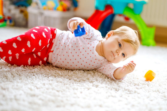 Little cute baby girl learning to crawl. Healthy child crawling in kids room with colorful toys. Back view of baby legs. Cute toddler discovering home and learning different skills