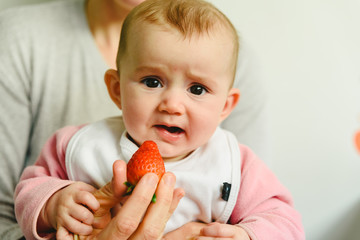 Baby starting by tasting a strawberry using the Baby led weaning BLW method.