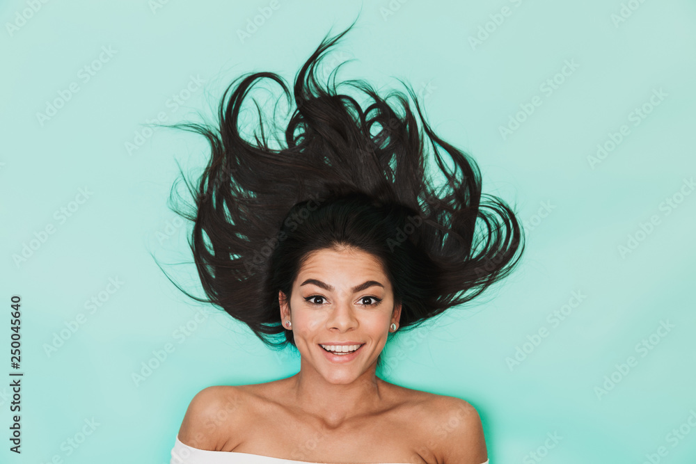 Sticker beautiful young woman lies isolated on blue light background. healthy hair concept.